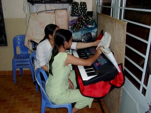 A sister is teaching a girl keyboard.